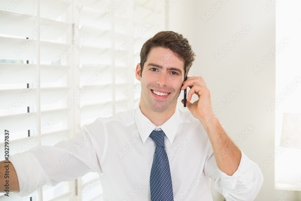 Smiling businessman using mobile phone in office Smiling businessman using mobile phone in office