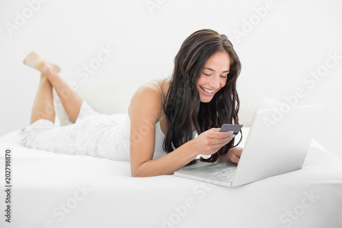 Casual woman doing online shopping in bed