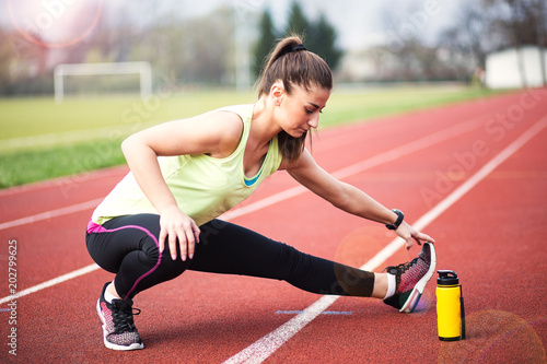 Sporty woman relaxing and stretching on athletic race track