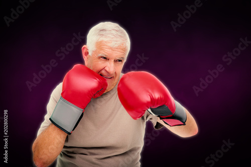 Close-up portrait of a determined senior boxer against dark background
