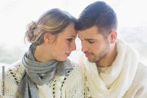 Loving couple in winter clothing against bright background