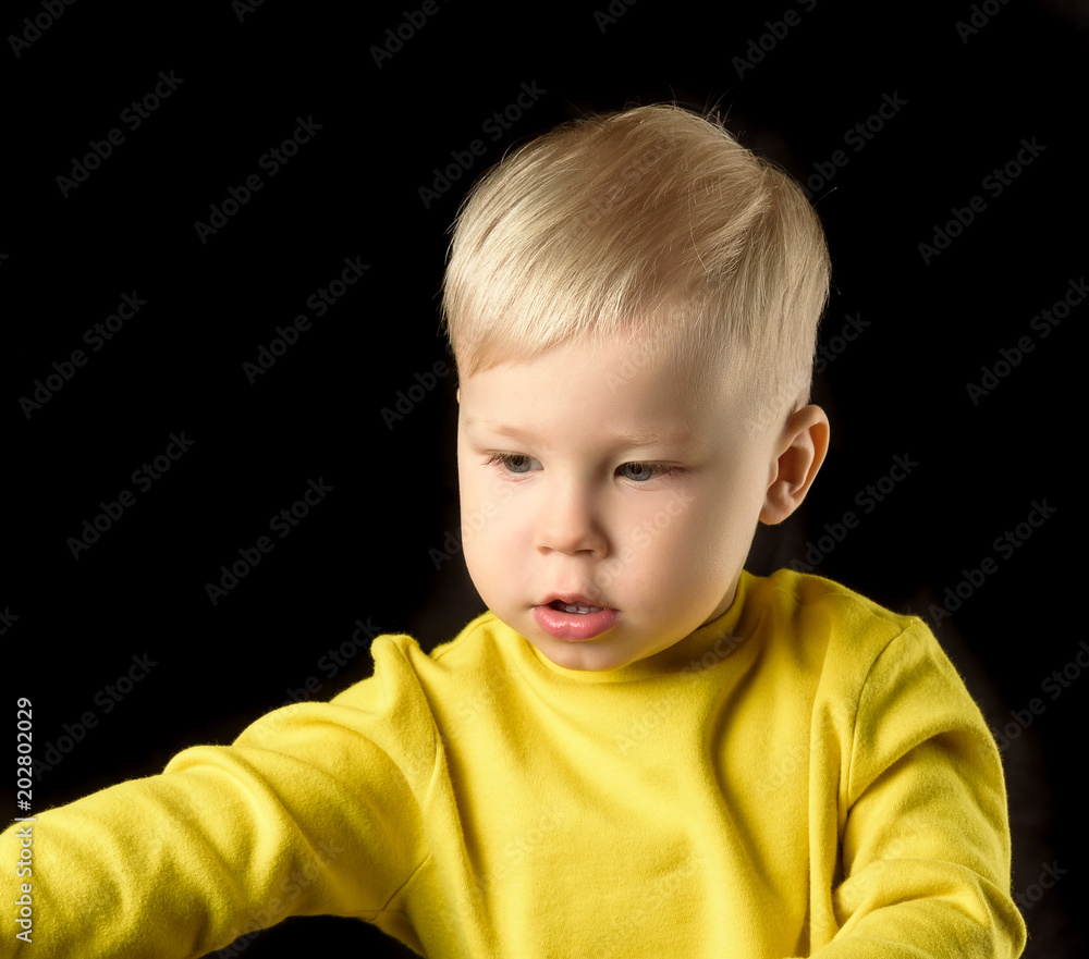 portrait of a fair-haired boy in a yellow jacket on a black background portrait of a fair-haired boy in a yellow jacket on a black background