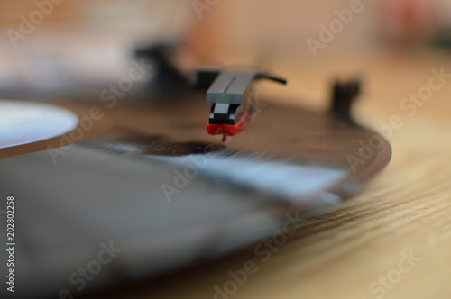 Closeup of tonearm and stylus on a wooden vinyl record player