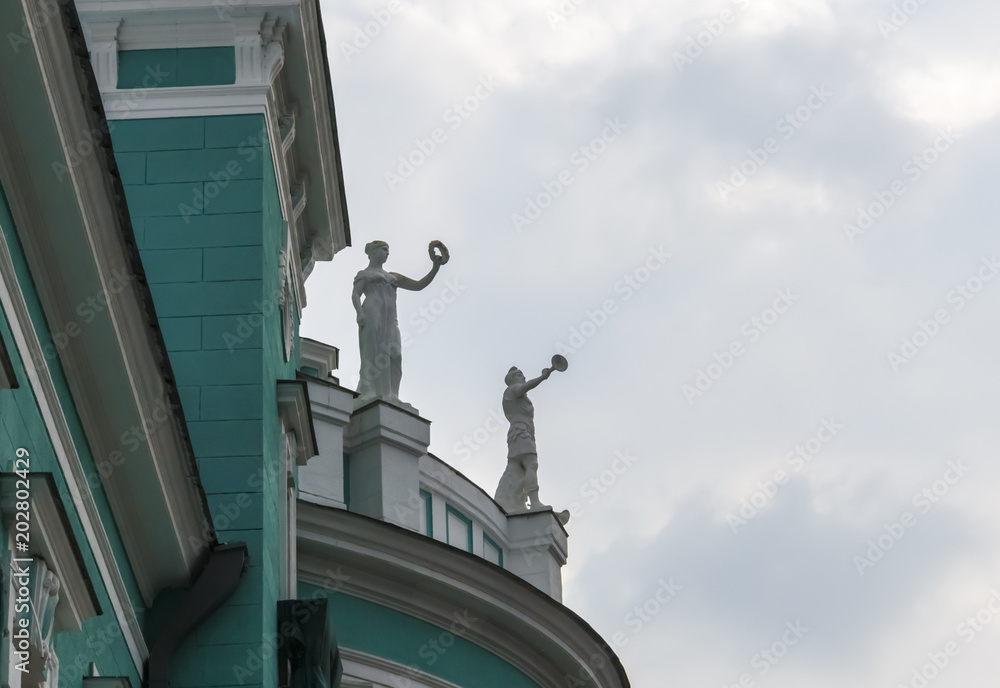 ancient statues on the roof of an old green house.