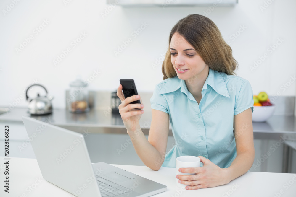 Content brunette woman making use of her smartphone holding a cup Content brunette woman making use of her smartphone holding a cup