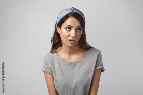 Fotografi Funny emotional young Caucasian woman wearing gray top and headscarf grimacing, rolling her eyes, expressing annoyance, pissed off or bored with something