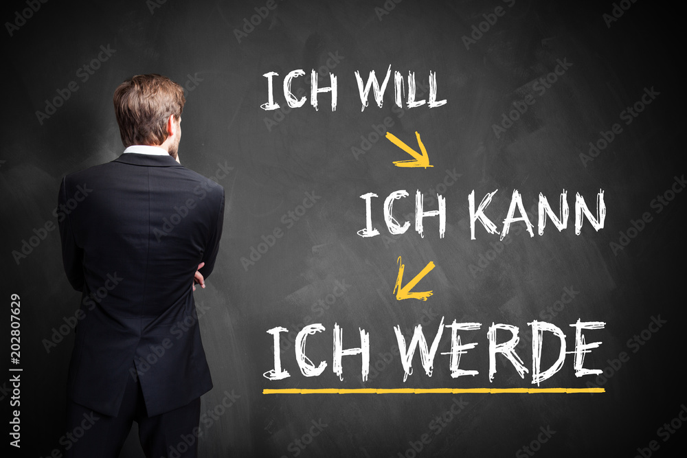 Geschäftsmann schaut auf Tafel mit Prozess der Selbstmotivation Geschäftsmann schaut auf Tafel mit Prozess der Selbstmotivation