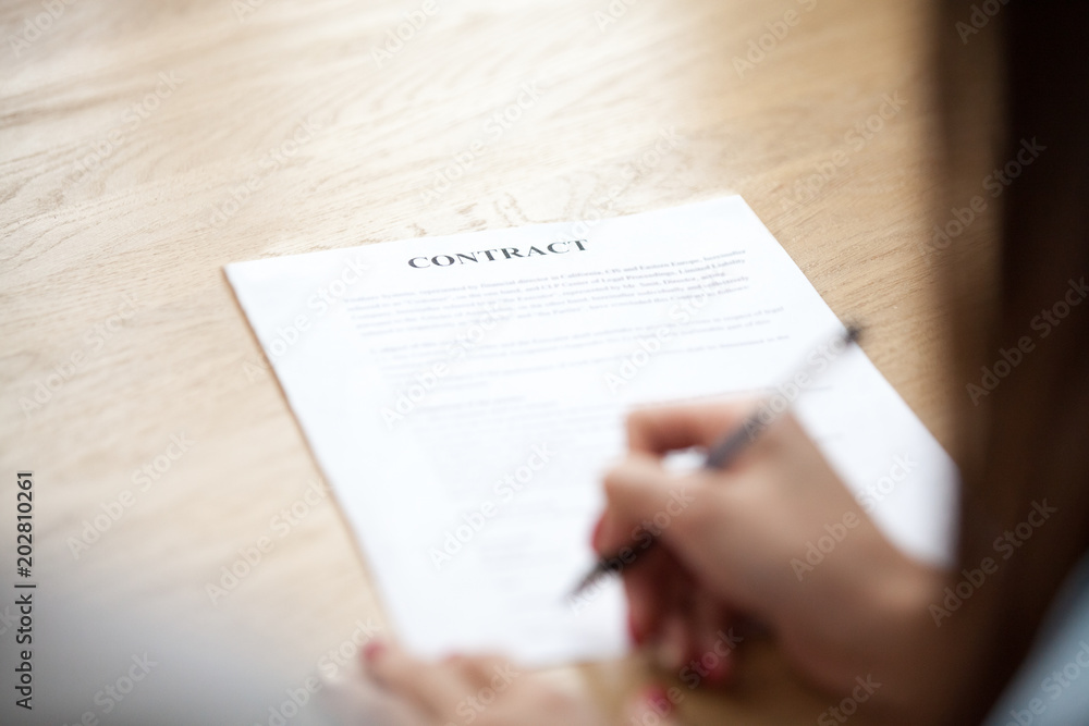 Naklejka premium Female hand putting signature on business contract, woman client agreeing on terms making sale purchase deal signing legal paper, mortgage, insurance, loan or employment concept, focus on document
