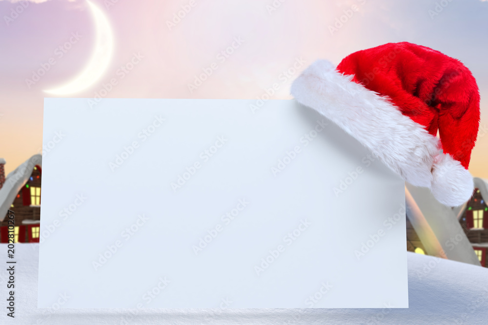 Santa hat on poster against cute christmas village under crescent moon Santa hat on poster against cute christmas village under crescent moon