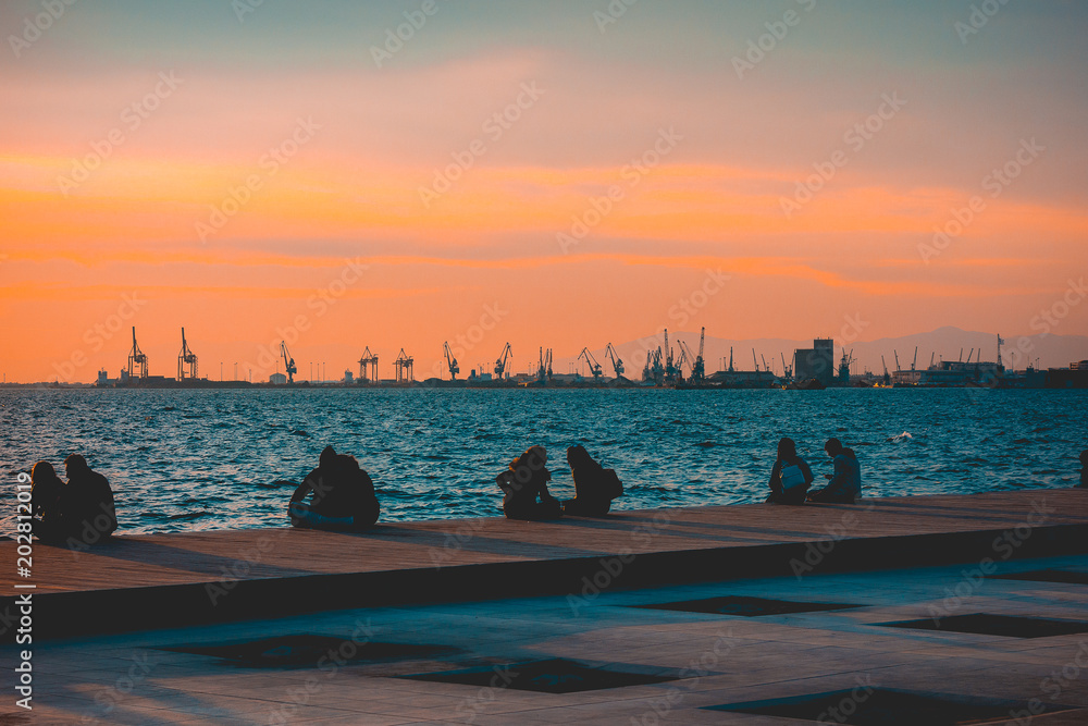 People sitting on a quay enjoying a sunset