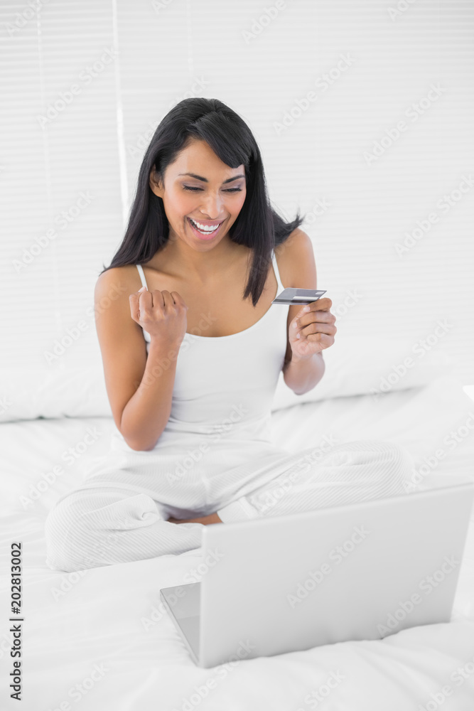 Content cheering woman home shopping with her laptop Content cheering woman home shopping with her laptop