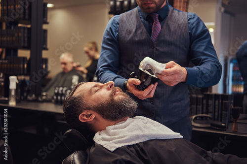 A master hairdresser prepares the face for shaving, deals foam.