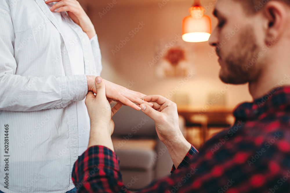 Man puts the wedding ring on the finger of beloved