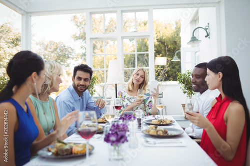 Happy friends interacting with each other while having meal