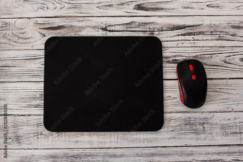 Φωτογραφία Black computer mousepad with a mouse on a white wooden background