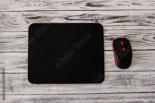 Black computer mousepad with a mouse on a white wooden background photo