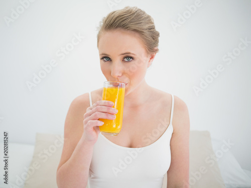 Natural content blonde drinking a glass of orange juice
