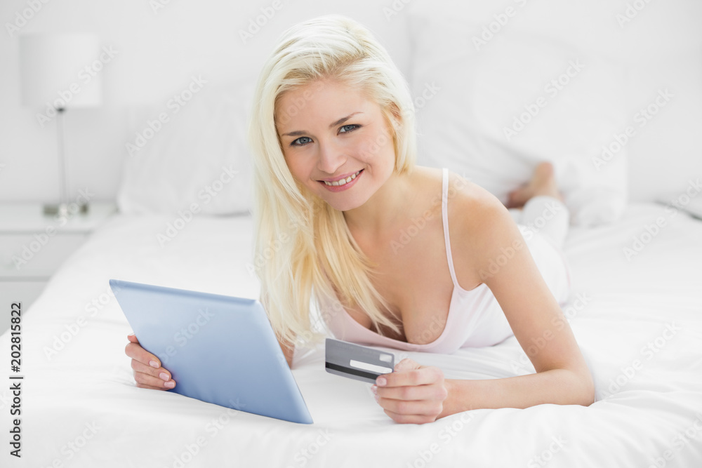 Casual young blond doing online shopping in bed Casual young blond doing online shopping in bed