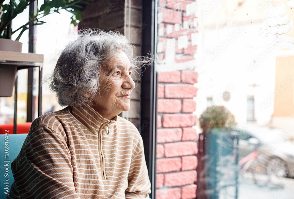 Fotografie Senior woman looking through window