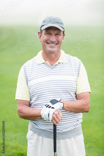 Cheerful golfer smiling at camera holding his club