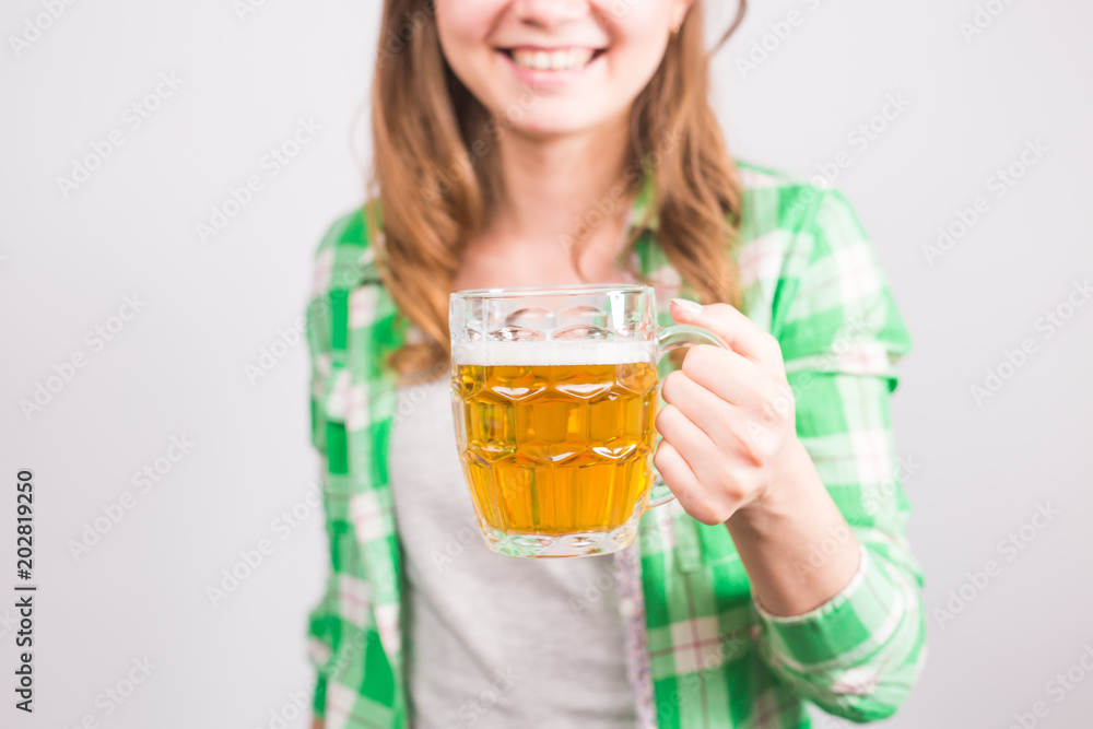 Closeup of young woman holding a beer mug full of beer and smiling on white background Closeup of young woman holding a beer mug full of beer and smiling on white background