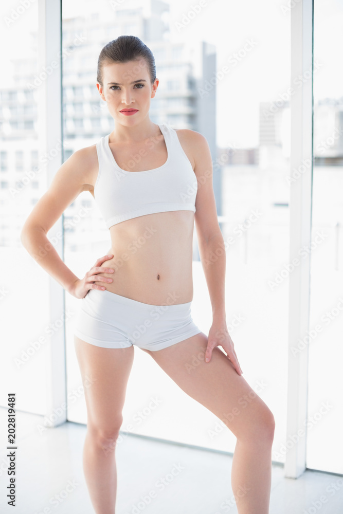 Serious fit brown haired model in sportswear posing looking at camera