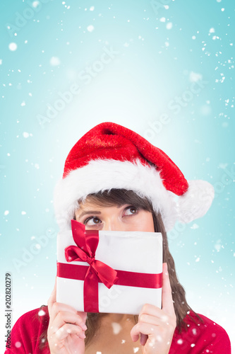 Portrait of a festive young woman holding a gift against blue vignette © vectorfusionart