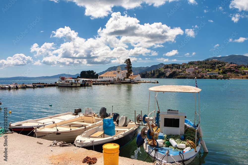 Fisher boats and the Panagia Vlacherna monastery in the backgorund with a nice cloudscape in Corfu, Greece