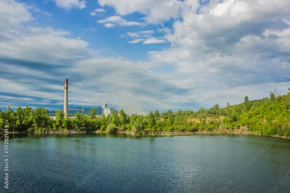 quarry nature hill landscape with lake and industrial factory on background pollution concept