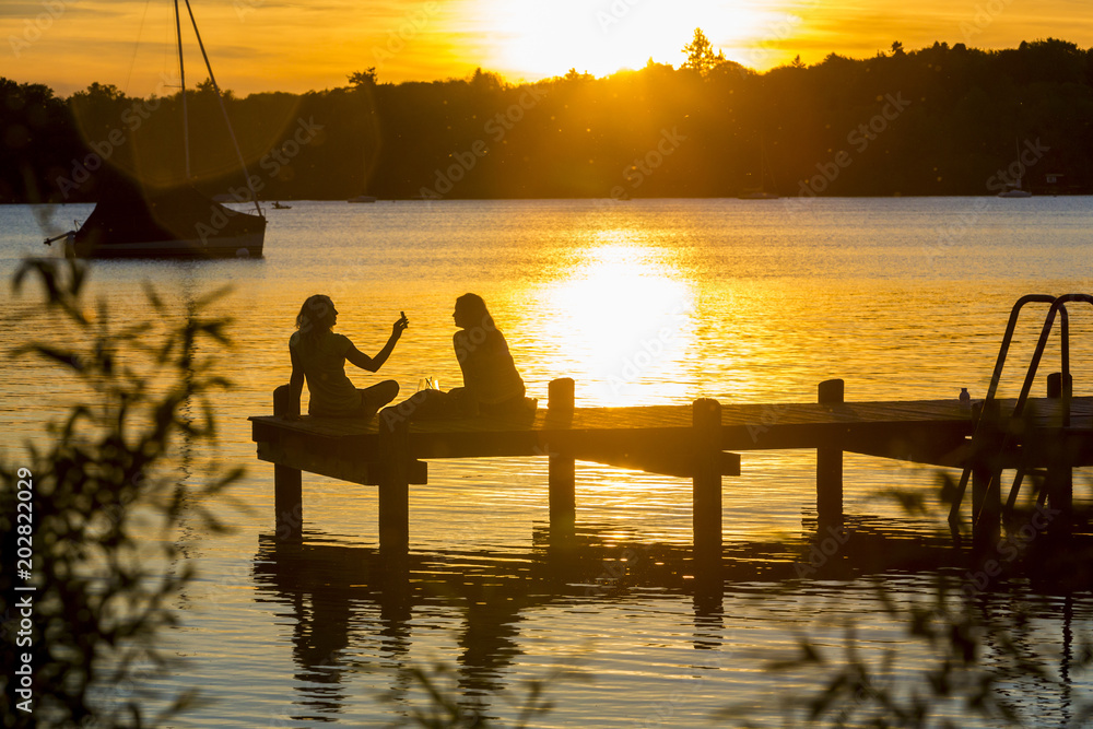 Zwei Frauen am See geniessen den Sonnenuntergang