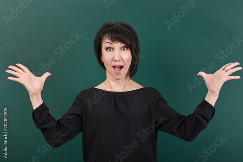 teacher having idea and posing by chalk Board, learning concept, green background, Studio shot