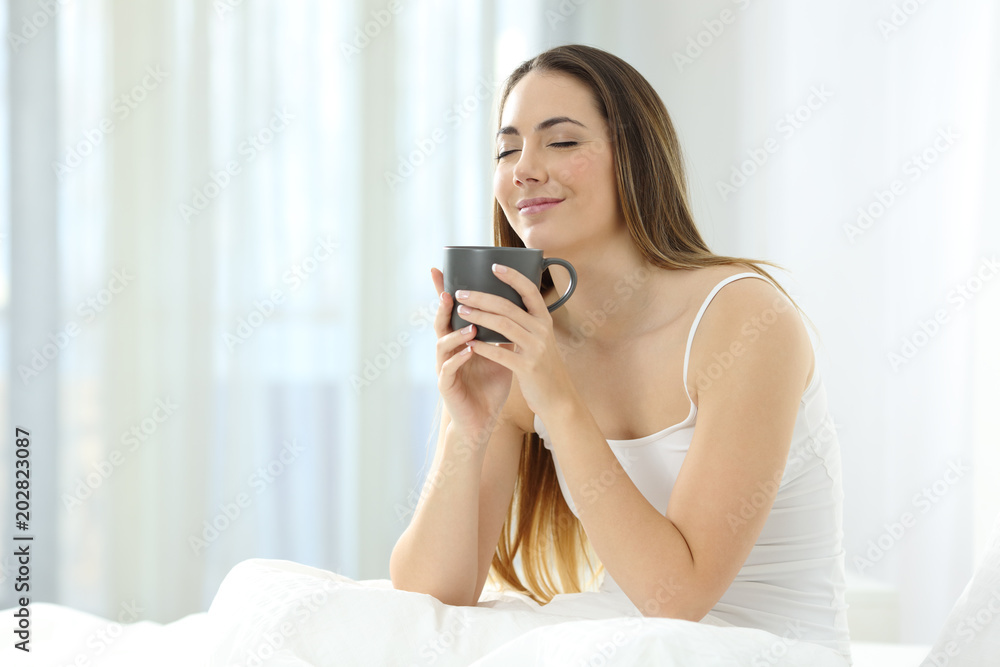 Woman waking up enjoying a cup of coffee on the bed Woman waking up enjoying a cup of coffee on the bed