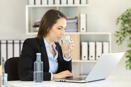 Office worker drinking water working on line