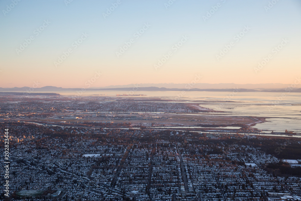 Aerial view of the City and Airport in the Distance during a vibrant sunset. Taken in Vancouver, British Columbia, Canada.