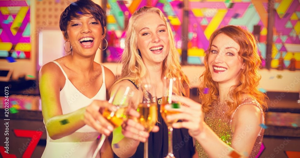 Portrait of three smiling friend toasting glass of champagne against flying colours Portrait of three smiling friend toasting glass of champagne against flying colours