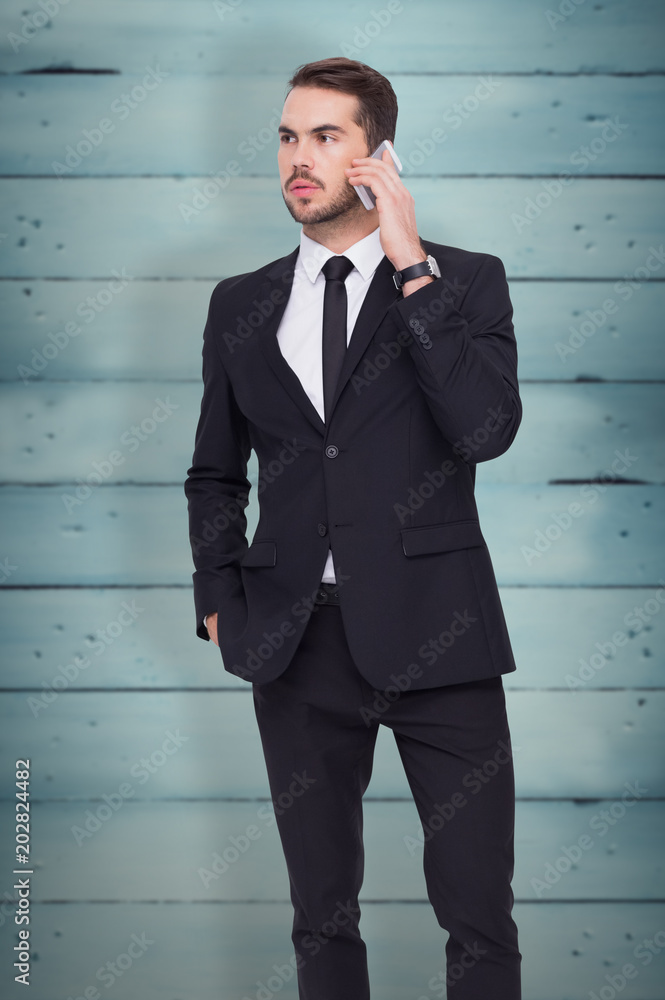 Serious businessman hand in pocket phoning against wooden planks Serious businessman hand in pocket phoning against wooden planks