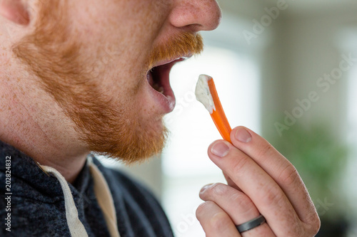 Man Eating Carrot with Ranch Dressing