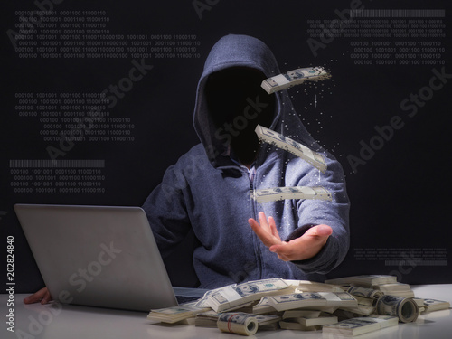 Cyber attack with unrecognizable hooded hacker.Hacker steal money in the office.