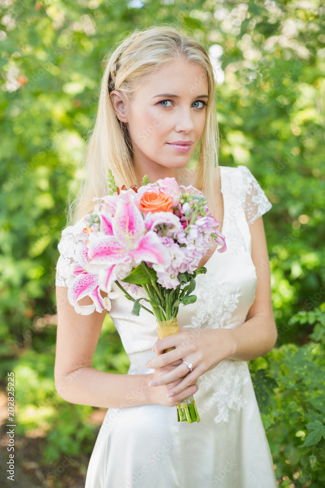 Blonde bride holding bouquet smiling at camera Blonde bride holding bouquet smiling at camera