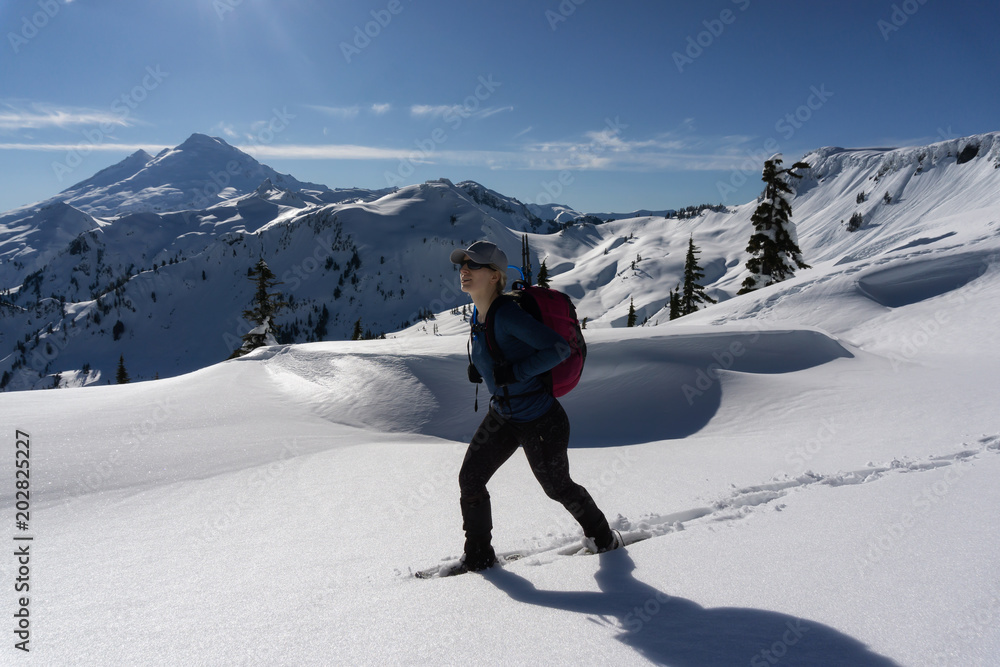 Adventurous woman is snowshoeing in the beautiful mountainous landscape. Taken in Artist Point, Northeast of Seattle, Washington, United States of America.