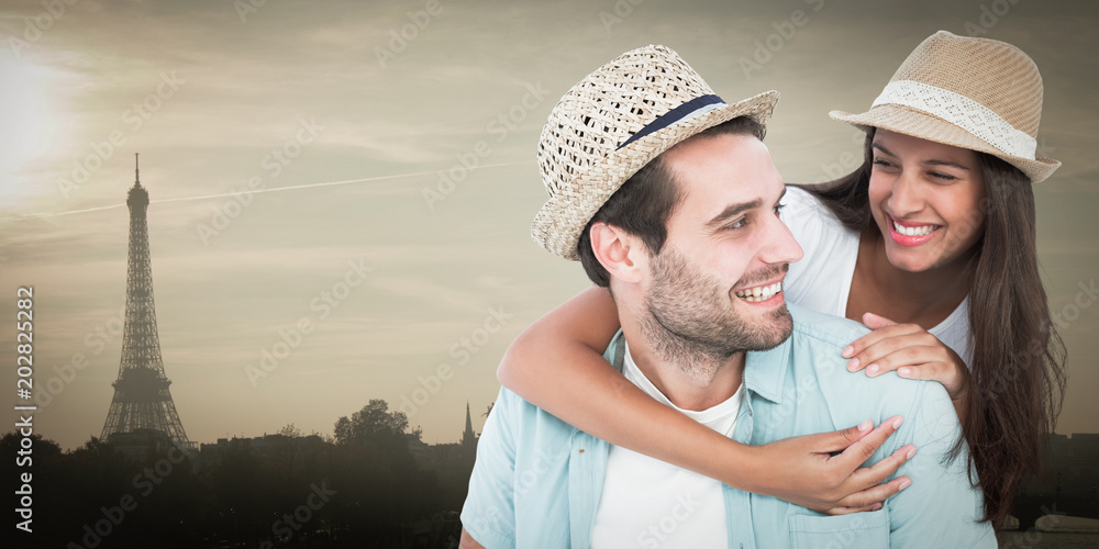 Happy casual man giving pretty girlfriend piggy back against eiffel tower