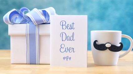 Happy Father's Day close up of Best Dad Ever greeting card and coffee mug on table.