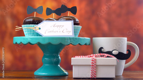 Happy Father's Day close up of gift, cupcakes and coffee mug against rustic wood background. photo