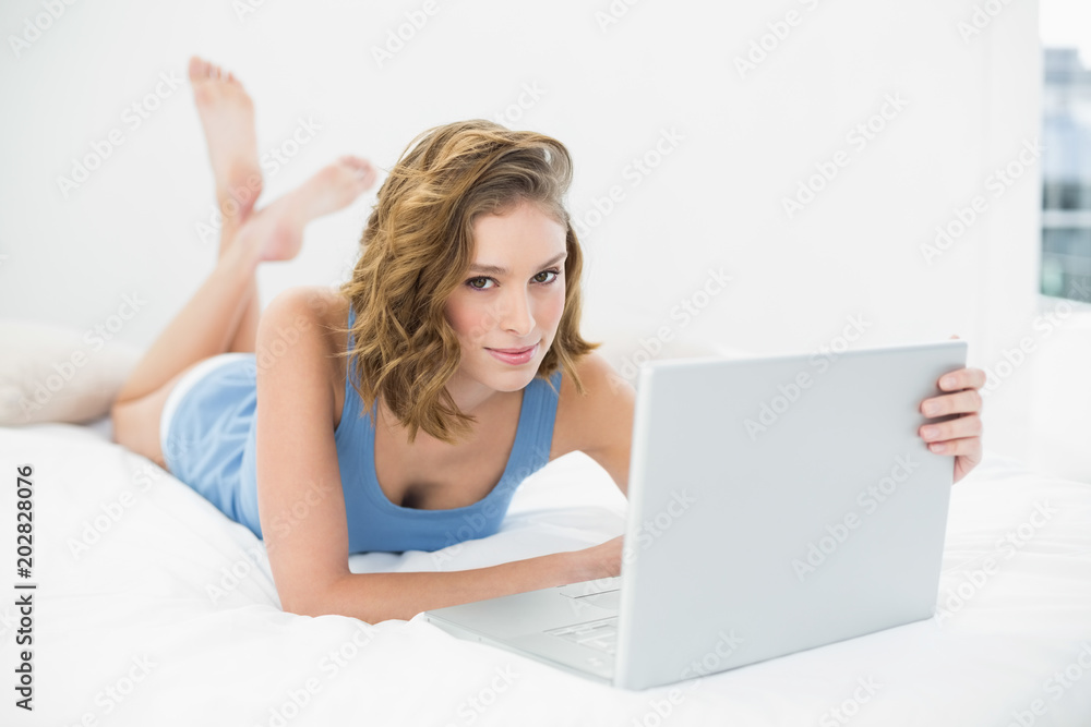 Attractive calm woman using her white notebook looking at camera Attractive calm woman using her white notebook looking at camera