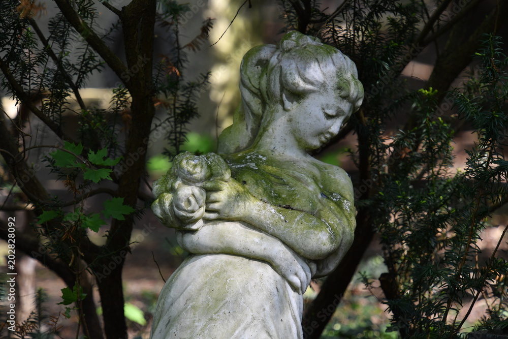 With moss covered sculpture of a woman on a tomb of the cemetery in Berlin-Charlottenburg