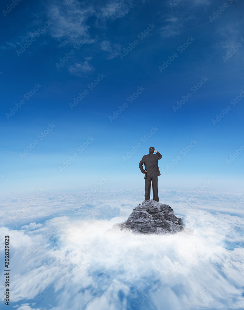 Mature businessman looking and considering against mountain peak through the clouds Mature businessman looking and considering against mountain peak through the clouds