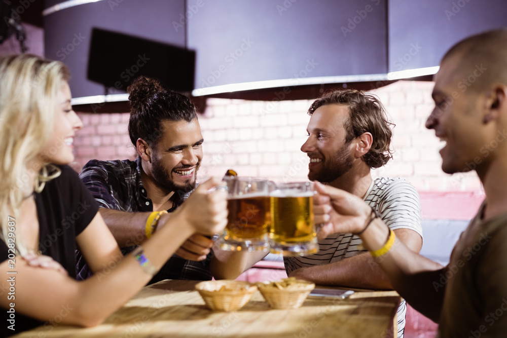 Happy friends toasting beer mugs at nightclub