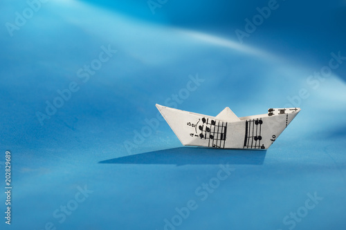 Paper boat made of musical score sheet in blue background