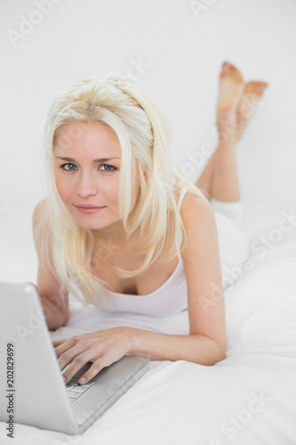 Casual relaxed young blond with laptop in bed