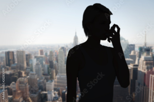 Blonde woman taking her inhaler against new york